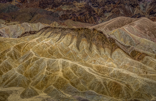 View of the rugged eroded badlands of Death Valley National Park s backcountry with intricate golden brown ridges and deep shadows in Death Valley California United States.