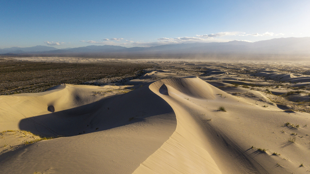Aerial view of Dunas de Taton featuring vast golden sand dunes wind swept ridges and distant mountain ranges in Tinogasta Department Catamarca Province Argentina. Aerial view of Dunas de Taton featuring vast golden sand dunes wind swept ridges and distant mountain ranges in Tinogasta Department Catamarca Province Argentina.