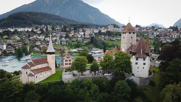 Aerial view of Schloss Spiez and the historic Schlosskirche church overlooking Lake Thun with the Bernese Alps and town houses in the background Spiez Bern Switzerland. Aerial view of Schloss Spiez and the historic Schlosskirche church overlooking Lake Thun with the Bernese Alps and town houses in the background Spiez Bern Switzerland.