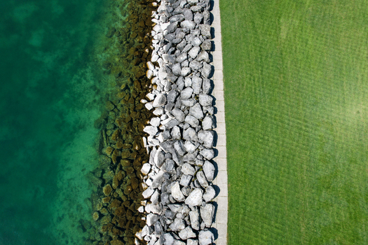 Aerial view of the rocky shoreline of Lake Geneva with turquoise water and a lush green lawn Morges Vaud Switzerland. Aerial view of the rocky shoreline of Lake Geneva with turquoise water and a lush green lawn Morges Vaud Switzerland.