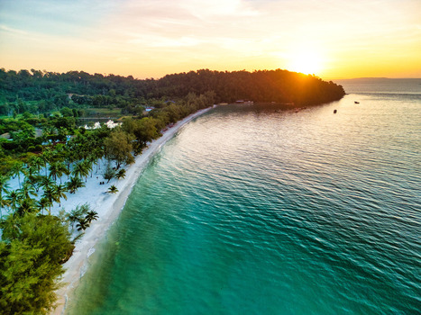 Aerial view of the soft white sands kissed by the turquoise sea where the lush green forest meets the horizon at sunset Preah Sihanouk Sihanoukville Cambodia.
