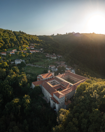 Aerial view of Monastery of Santo Estevo de Ribas de Sil nestled in the lush green hills of the Ribeira Sacra region at sunset O Covelo Ourense Spain.