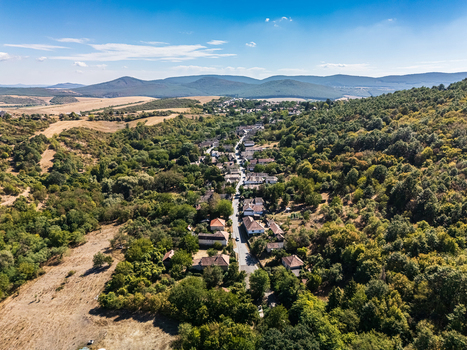 Aerial view of Holloko s traditional old village with houses lining a valley road amid forested hills farmland and the rural landscape of northern Hungary. Aerial view of Holloko s traditional old village with houses lining a valley road amid forested hills farmland and the rural landscape of northern Hungary.