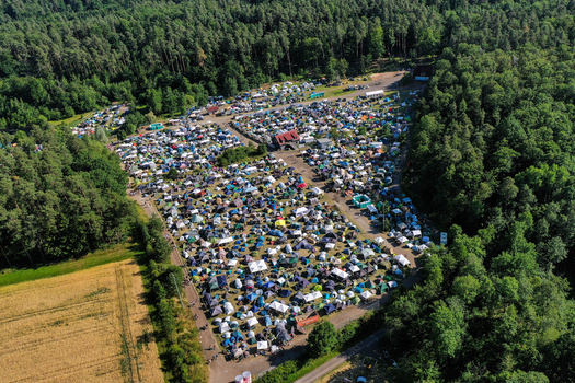 Aerial view of the crowded campsite at Eventzentrum Strohofer with numerous tents surrounded by dense green forest and fields in Geiselwind Bayern Germany. Aerial view of the crowded campsite at Eventzentrum Strohofer with numerous tents surrounded by dense green forest and fields in Geiselwind Bayern Germany.