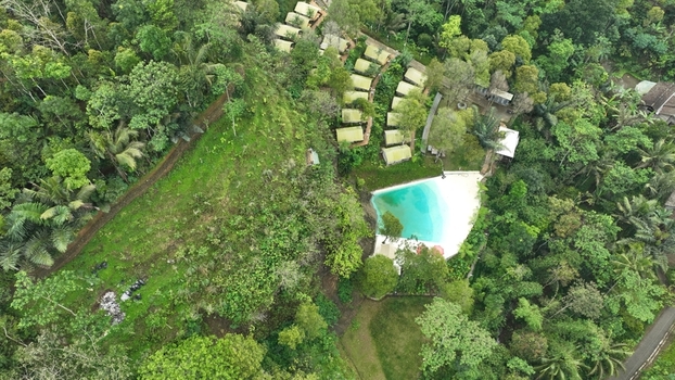 Aerial view of Glamping Menoreh featuring luxury tents nestled in lush tropical forest with a swimming pool in Kecamatan Samigaluh Daerah Istimewa Yogya Indonesia. Aerial view of Glamping Menoreh featuring luxury tents nestled in lush tropical forest with a swimming pool in Kecamatan Samigaluh Daerah Istimewa Yogya Indonesia.