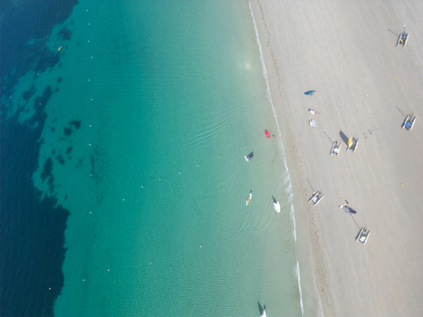 Aerial view of turquoise sea water meeting a sandy beach with small boats and people in Trebeurden Brittany France. Aerial view of turquoise sea water meeting a sandy beach with small boats and people in Trebeurden Brittany France.