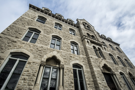 View of a historic stone building with gothic style arched windows and intricate masonry under a cloudy sky in Lincoln Nebraska United States.