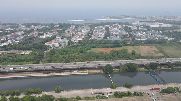 Aerial view of a busy highway running alongside a canal with residential buildings and lush greenery in Tanjung Priok Jakarta Indonesia. Aerial view of a busy highway running alongside a canal with residential buildings and lush greenery in Tanjung Priok Jakarta Indonesia.