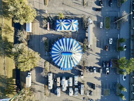 Aerial view of vibrant blue and white circus tents nestled within a sprawling parking lot surrounded by trees St. Augustine Florida United States. Aerial view of vibrant blue and white circus tents nestled within a sprawling parking lot surrounded by trees St. Augustine Florida United States.