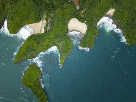 Aerial view of Sedahan Beach where green cliffs meet deep blue ocean white waves on golden sands Gunungkidul Regency Special Region of Yogyakarta Indonesia. Aerial view of Sedahan Beach where green cliffs meet deep blue ocean white waves on golden sands Gunungkidul Regency Special Region of Yogyakarta Indonesia.