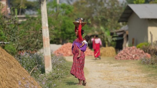 View of a woman carrying a baby and basket in Dhangadhi Nepal. View of a woman carrying a baby and basket in Dhangadhi Nepal.