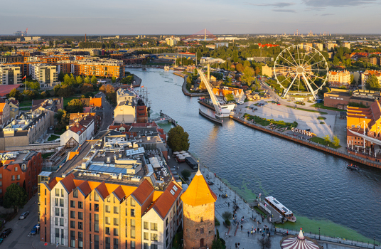 Aerial view of the Motlawa River featuring the AmberSky Ferris wheel historic brick buildings and the drawbridge during the golden hour in Gdansk Pomeranian Voivodeship Poland. Aerial view of the Motlawa River featuring the AmberSky Ferris wheel historic brick buildings and the drawbridge during the golden hour in Gdansk Pomeranian Voivodeship Poland.