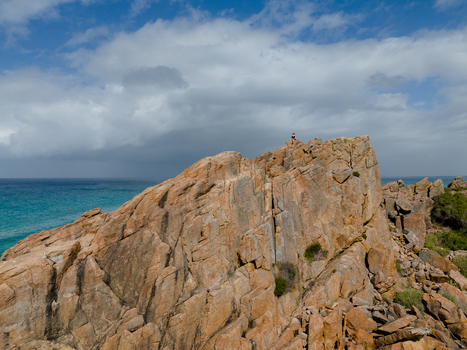 Aerial view of Castle Rock with a person on the summit overlooking turquoise ocean waters and granite formations in Dunsborough Western Australia Australia. Aerial view of Castle Rock with a person on the summit overlooking turquoise ocean waters and granite formations in Dunsborough Western Australia Australia.