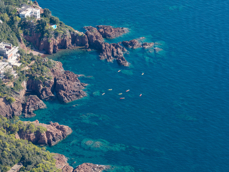 Aerial view of Le Trayas with red rock formations meeting the blue Mediterranean Sea featuring small kayaks near the rugged coastline in Saint Raphael Provence Alpes Cote d Azur France. Aerial view of Le Trayas with red rock formations meeting the blue Mediterranean Sea featuring small kayaks near the rugged coastline in Saint Raphael Provence Alpes Cote d Azur France.