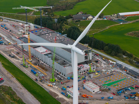 Aerial view of the Green Mountain data center construction site in Undheim featuring a large wind turbine cranes and industrial equipment set against green fields in Rogaland Norway. Aerial view of the Green Mountain data center construction site in Undheim featuring a large wind turbine cranes and industrial equipment set against green fields in Rogaland Norway.