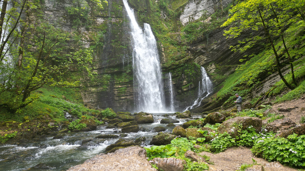 Aerial view of Cascades du Flumen waterfall cascading down rocky cliffs into a stream surrounded by lush green forest in Septmoncel Les Molunes Bourgogne Franche Com France. Aerial view of Cascades du Flumen waterfall cascading down rocky cliffs into a stream surrounded by lush green forest in Septmoncel Les Molunes Bourgogne Franche Com France.