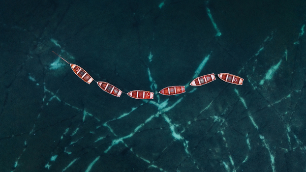 Aerial view of a line of wooden rowing boats floating on the turquoise water of Lake Braies in Braies Trentino Alto Adige Italy. Aerial view of a line of wooden rowing boats floating on the turquoise water of Lake Braies in Braies Trentino Alto Adige Italy.