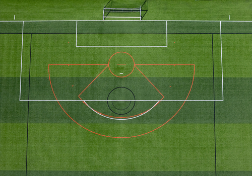 Aerial view of a soccer field featuring white boundary lines a red arc and a black center circle on green artificial turf in Kalamazoo Michigan United States. Aerial view of a soccer field featuring white boundary lines a red arc and a black center circle on green artificial turf in Kalamazoo Michigan United States.