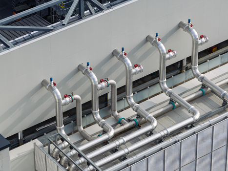 Aerial view of industrial piping and cooling system infrastructure on the exterior wall of a data center in the United Kingdom. Aerial view of industrial piping and cooling system infrastructure on the exterior wall of a data center in the United Kingdom.