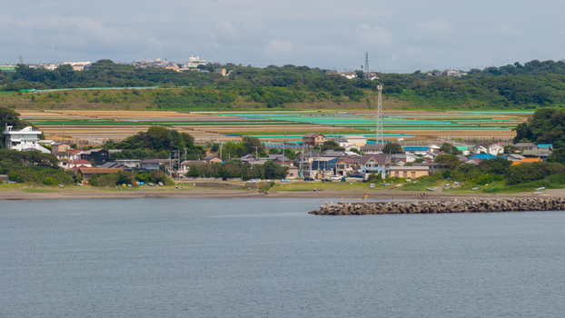 Aerial view of a coastal village with agricultural fields a small breakwater and houses near the sea in Japan. Aerial view of a coastal village with agricultural fields a small breakwater and houses near the sea in Japan.