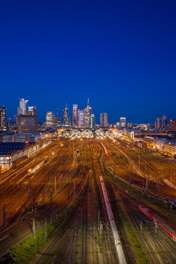 Aerial view of Hauptbahnhof train station with illuminated tracks and the city skyline under a twilight sky Frankfurt am Main Hessen Germany.