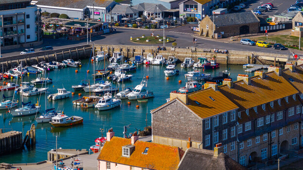 Aerial view of the harbour filled with various small boats and yachts surrounded by historic buildings and coastal infrastructure in West Bay England United Kingdom. Aerial view of the harbour filled with various small boats and yachts surrounded by historic buildings and coastal infrastructure in West Bay England United Kingdom.