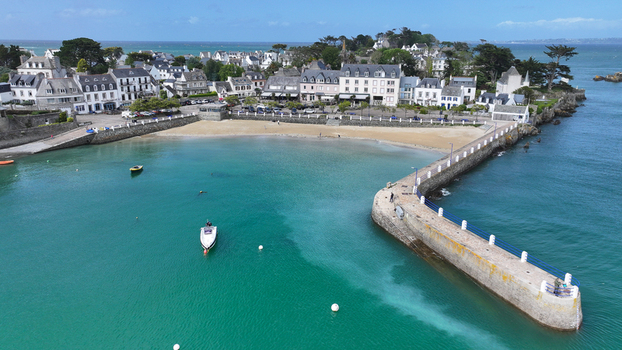 Aerial view of the picturesque harbor of Locquirec featuring a stone pier sandy beach and traditional coastal houses along the turquoise sea Locquirec Brittany France. Aerial view of the picturesque harbor of Locquirec featuring a stone pier sandy beach and traditional coastal houses along the turquoise sea Locquirec Brittany France.