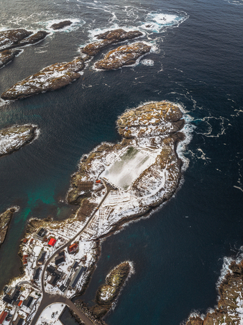 Aerial view of snow dusted islands and rocky outcrops contrasting with the deep blue sea connected by winding paths Henningsv&aelig;r Nordland Norway.