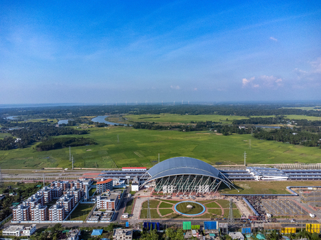 Aerial view of the modern Cox s Bazar Railway Station featuring a distinctive curved roof surrounded by lush green fields and infrastructure in Cox s Bazar Chittagong Division Bangladesh. Aerial view of the modern Cox s Bazar Railway Station featuring a distinctive curved roof surrounded by lush green fields and infrastructure in Cox s Bazar Chittagong Division Bangladesh.