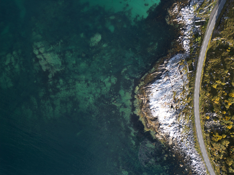 Aerial view of the turquoise sea meeting a rocky coastline with a winding road near Vik Strand in Leknes Nordland Norway. Aerial view of the turquoise sea meeting a rocky coastline with a winding road near Vik Strand in Leknes Nordland Norway.