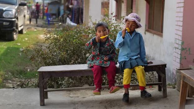 View of two children eating popsicles on a bench Nepal.