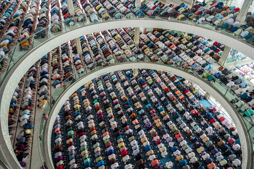 Dhaka Bangladesh 19 June 2026 Aerial view of a large congregation of people praying inside a modern mosque with curved balconies and patterned floors.