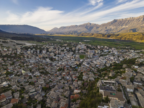 Aerial view of historic Gjirokaster with its traditional stone rooftops nestled in a valley surrounded by mountains under golden hour light in Gjirokaster Gjirokaster County Albania. Aerial view of historic Gjirokaster with its traditional stone rooftops nestled in a valley surrounded by mountains under golden hour light in Gjirokaster Gjirokaster County Albania.