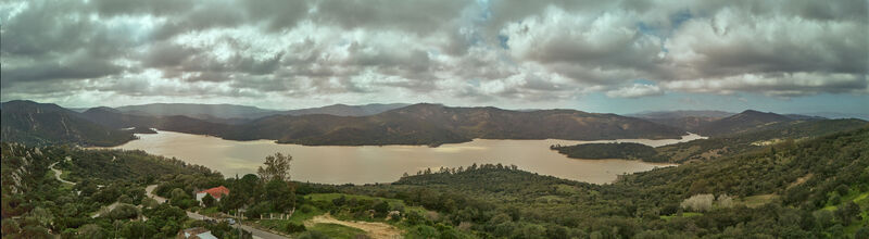 Aerial view of expansive reservoir reflecting the muted sky nestled amid rolling hills and verdant forests Castellar de la Frontera Andalucía Spain. Aerial view of expansive reservoir reflecting the muted sky nestled amid rolling hills and verdant forests Castellar de la Frontera Andalucía Spain.