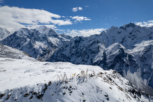 Aerial view of snow covered Himalayan peaks and deep valleys with colorful prayer flags fluttering in the wind Nepal.