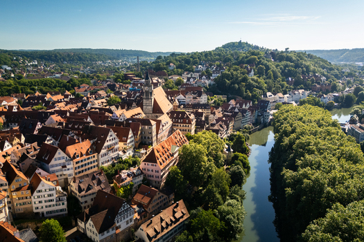 Aerial view of the historic old town with the Stiftskirche church traditional red roofed houses and the Neckar river lined with lush green trees in Tubingen Baden Wurttemberg Germany. Aerial view of the historic old town with the Stiftskirche church traditional red roofed houses and the Neckar river lined with lush green trees in Tubingen Baden Wurttemberg Germany.