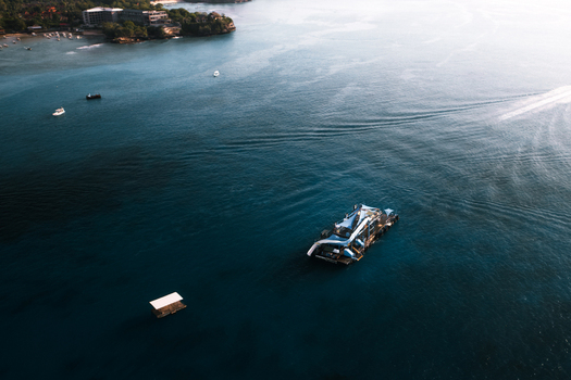 Aerial view of a floating platform in the clear blue waters of the ocean with small boats nearby near Lembongan Bali Indonesia.