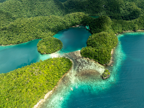 Aerial view of Bucas Grande featuring lush green islands surrounded by turquoise lagoons coral reefs and clear water with small boats in Siargao Philippines. Aerial view of Bucas Grande featuring lush green islands surrounded by turquoise lagoons coral reefs and clear water with small boats in Siargao Philippines.