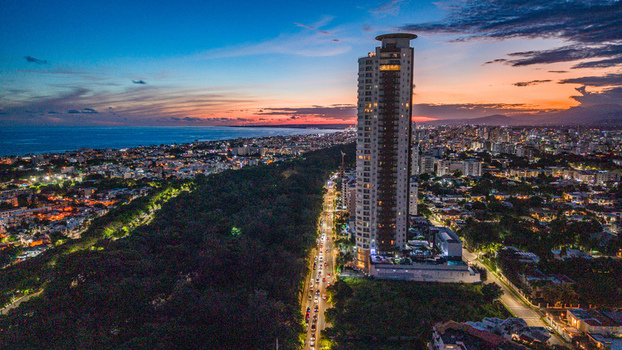 Aerial view of Caney Tower with its rooftop landing pad at twilight overlooking the urban landscape park and coastline in Santo Domingo Distrito Nacional Dominican Republic. Aerial view of Caney Tower with its rooftop landing pad at twilight overlooking the urban landscape park and coastline in Santo Domingo Distrito Nacional Dominican Republic.