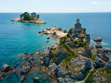 Aerial view of St. Nedjelja Church on a rocky islet surrounded by the clear blue Adriatic Sea with a second islet in the background Petrovac Montenegro. Aerial view of St. Nedjelja Church on a rocky islet surrounded by the clear blue Adriatic Sea with a second islet in the background Petrovac Montenegro.