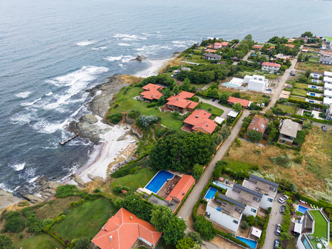 Aerial view of coastal villas with red tiled roofs private swimming pools and lush green gardens situated along the rocky shoreline of the Black Sea in Lozenets Burgas Bulgaria.