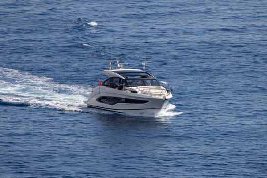 Aerial view of a sleek white motor yacht cruising through the deep blue Mediterranean Sea leaving a white wake behind in Monaco Monaco.