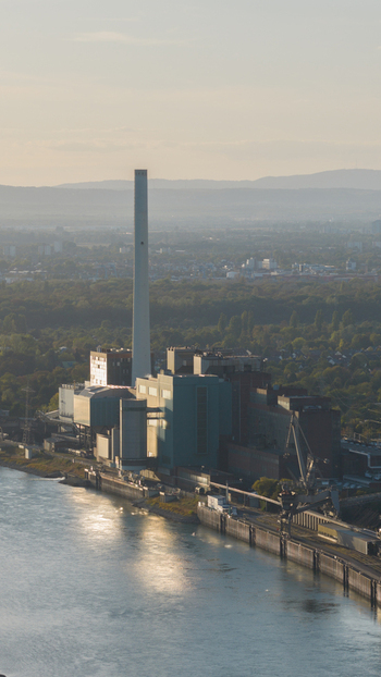 Aerial view of the Grosskraftwerk Mannheim power plant with its tall chimney and industrial buildings situated along the Rhine riverbank in Mannheim Baden Wurttemberg Germany.