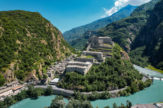 Aerial view of the historic Fortress of Bard perched on a rocky hill above the Dora Baltea river and the surrounding alpine mountains Bard Aosta Valley Italy.