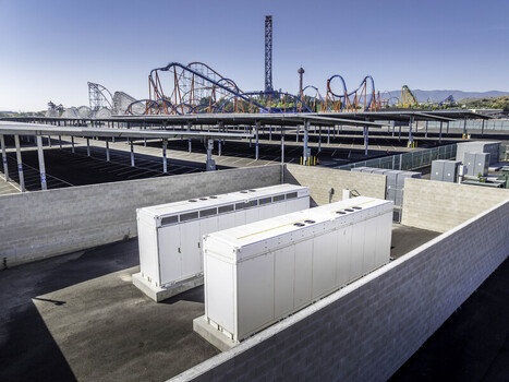Aerial view of Six Flags Magic Mountain featuring solar panel parking canopies and industrial battery storage units under a clear blue sky in Los Angeles County California United States. Aerial view of Six Flags Magic Mountain featuring solar panel parking canopies and industrial battery storage units under a clear blue sky in Los Angeles County California United States.