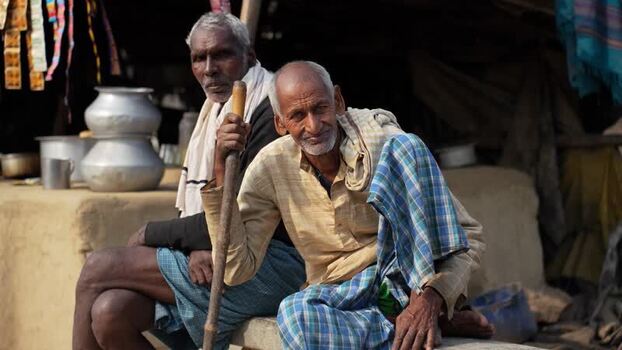 View of two elderly men sitting outside a rural home in Patna India.