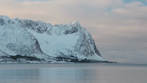 View of snow capped mountains over calm water Norway.