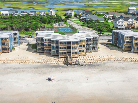 Aerial view of beachfront condominiums with wooden balconies sandbags along the dunes and a small tent on the sandy beach in North Topsail Beach North Carolina United States.