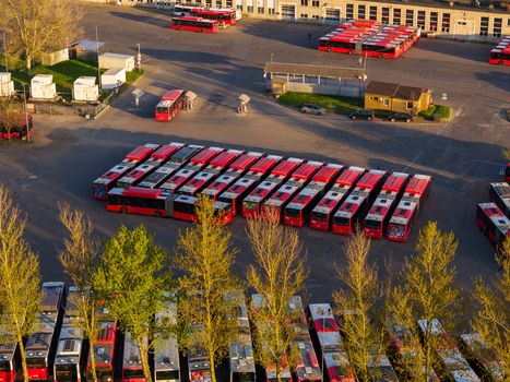 Vilnius County Lithuania 01 May 2026 Aerial view of numerous red public transport buses parked in a large depot during sunset with trees in the foreground. Vilnius County Lithuania 01 May 2026 Aerial view of numerous red public transport buses parked in a large depot during sunset with trees in the foreground.