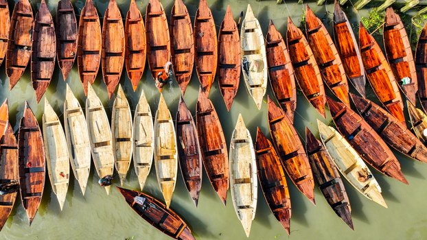 Aerial view of an array of wooden boats with rich warm tones contrasting with the cool green water Pirojpur Pourashava Barisal Division Bangladesh. Aerial view of an array of wooden boats with rich warm tones contrasting with the cool green water Pirojpur Pourashava Barisal Division Bangladesh.